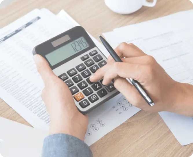 Working out a project cost on a calculator alongside printed estimates