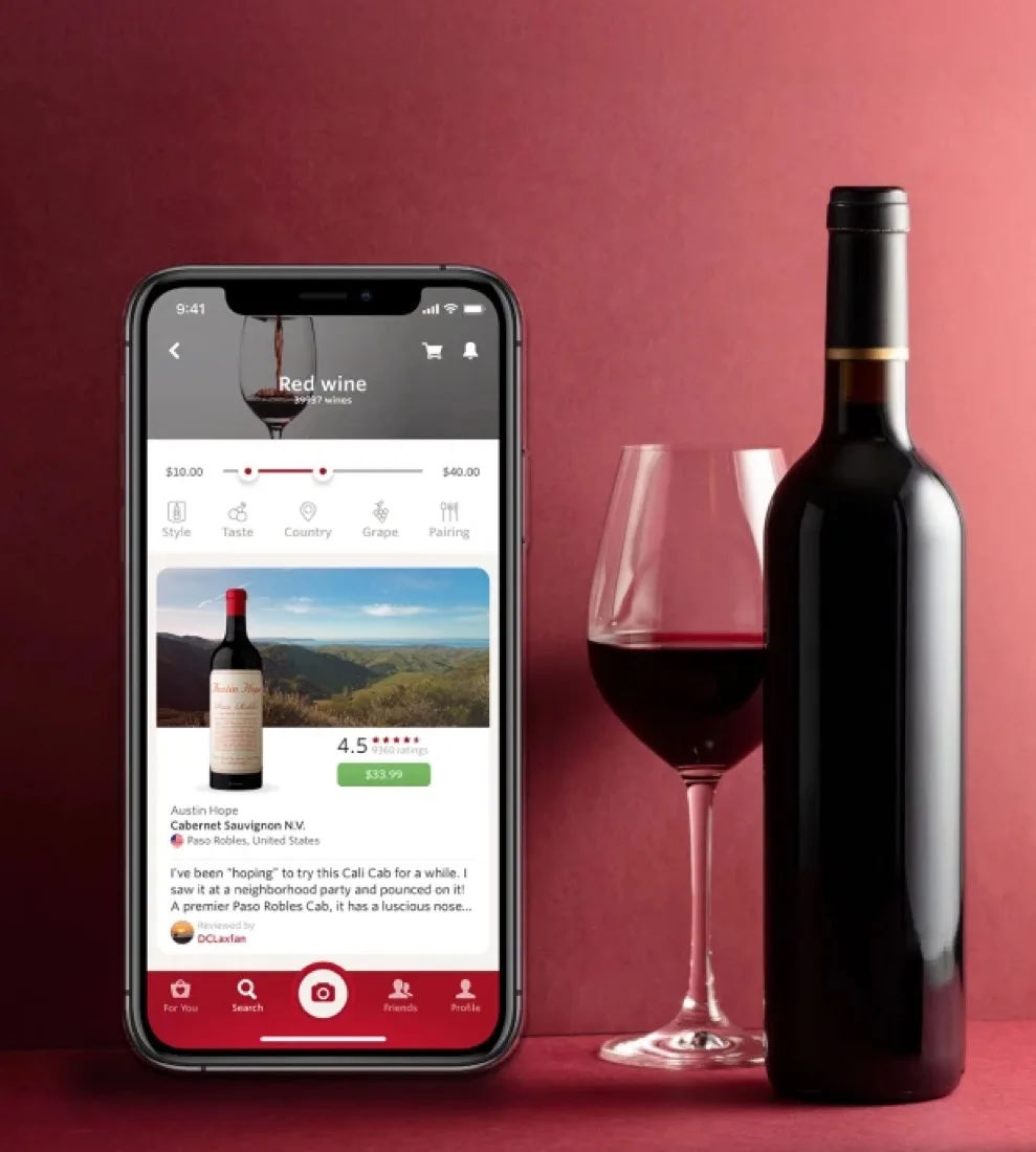 The Vivino app running on a phone beside a bottle and glass of red wine