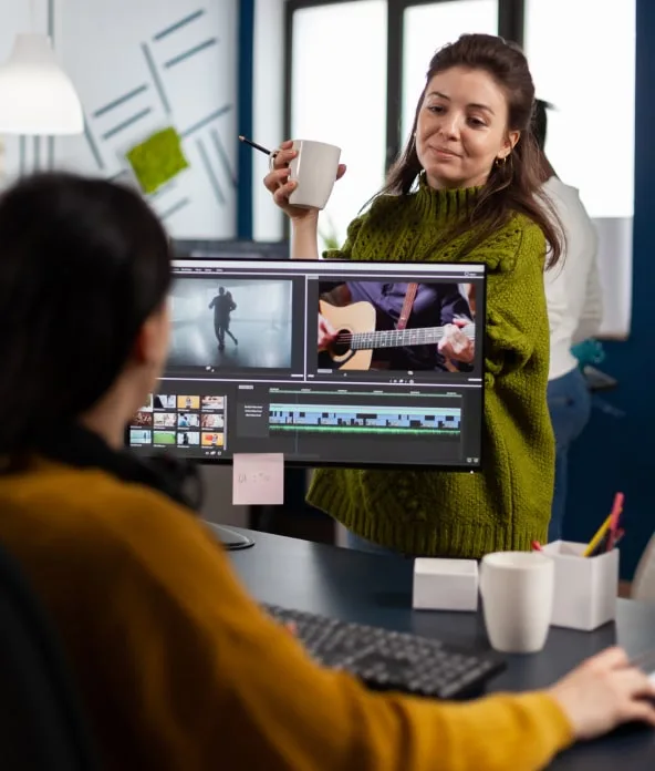 Two video editors reviewing a timeline of footage on a large monitor