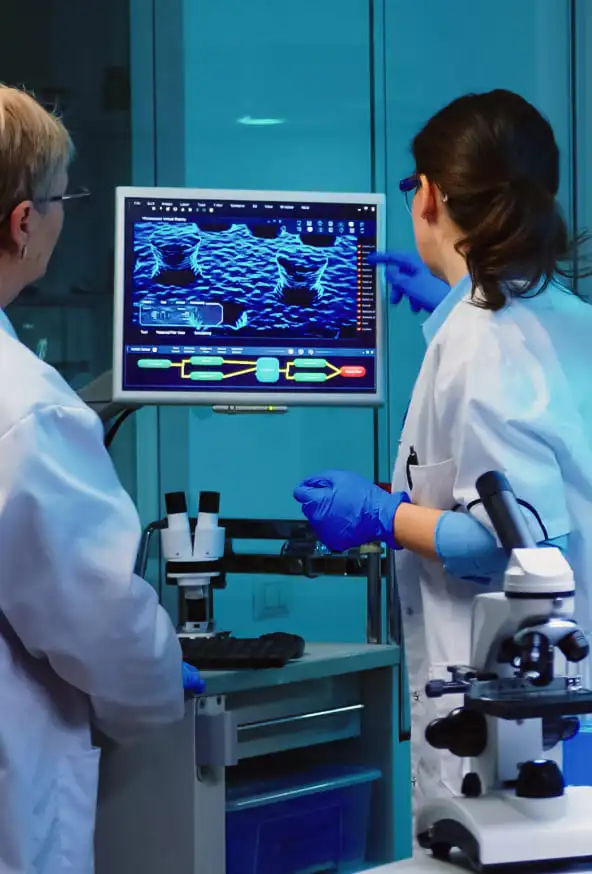 Two clinicians in a laboratory reviewing scan imagery on a monitor
