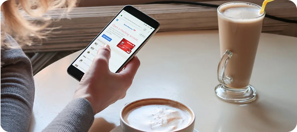 A customer ordering on their phone in a caf&eacute;, beside a cup of coffee